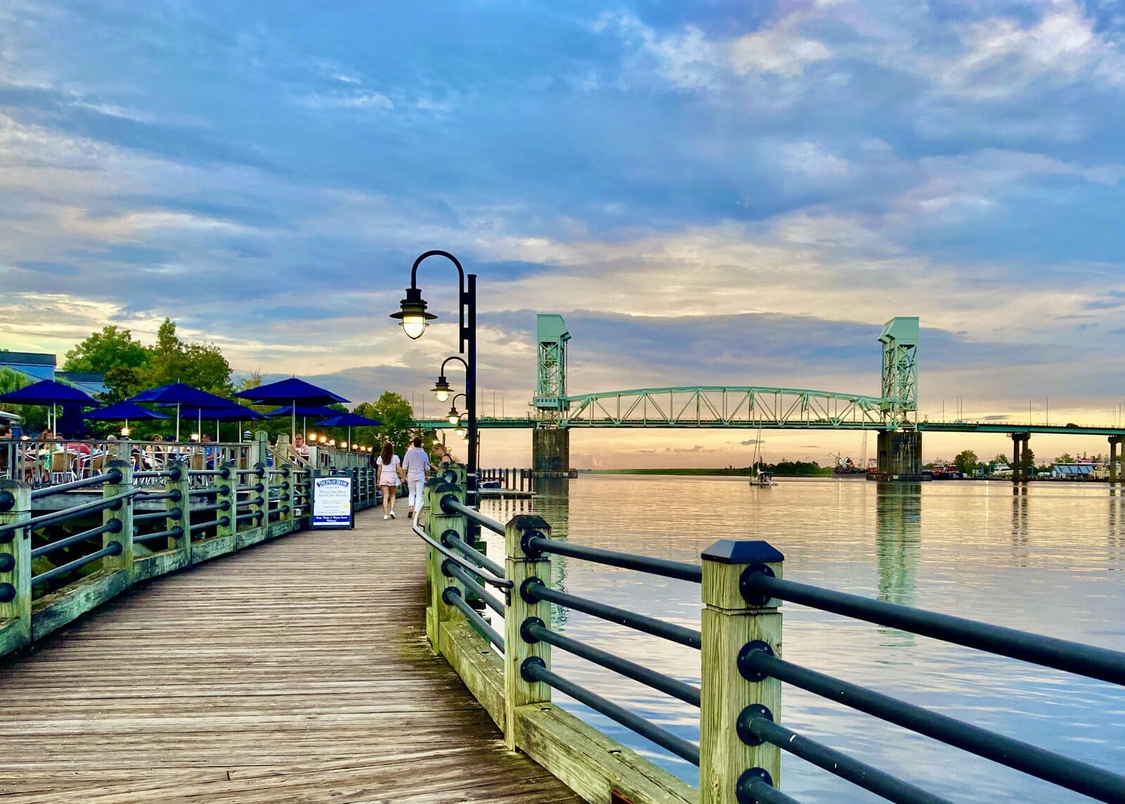 Wilmington NC Marathon: the wilmington riverwalk on the cape fear river at sunset, with the cape fear memorial bridge. the half marathon finishes at the cape fear river; this is not a photo of the race.