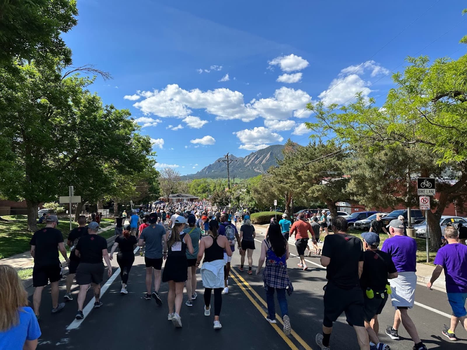 Boulderthon Marathon: runners on a boulder street heading toward the flatirons (bolderboulder 10k 2023, not boulderthon itself)