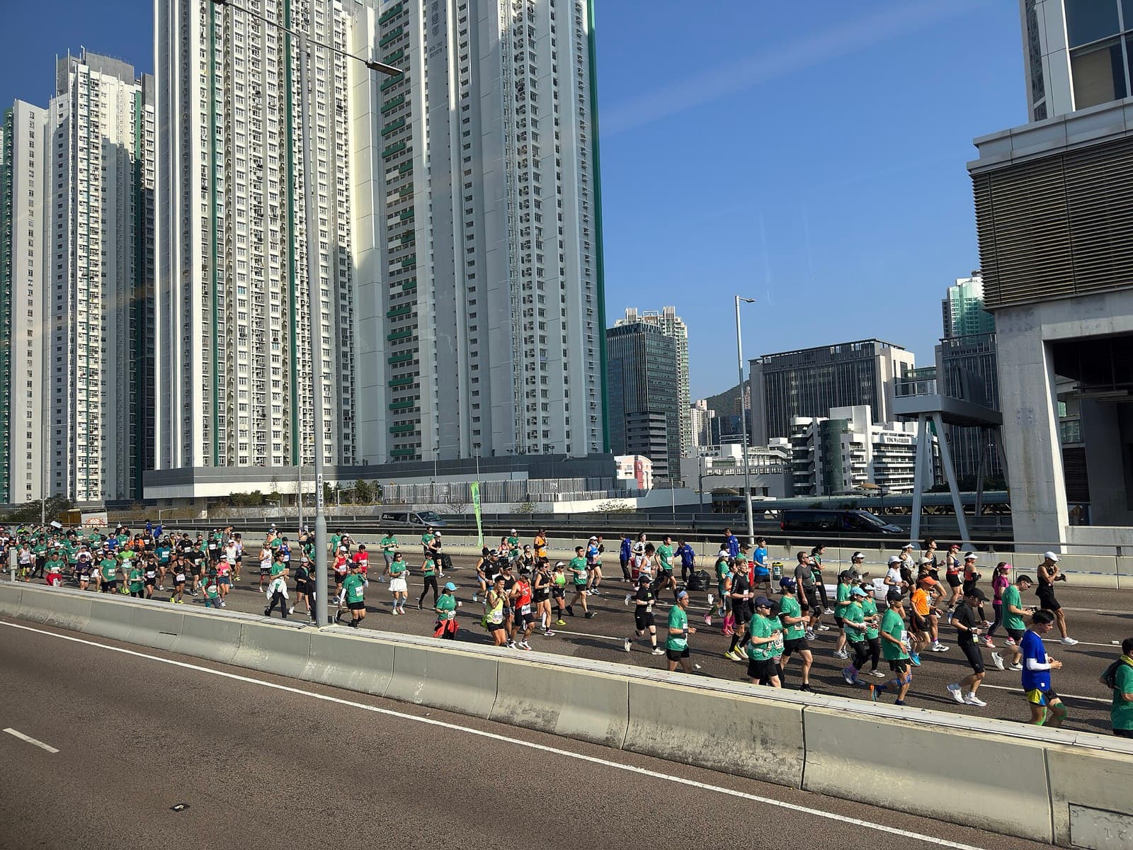 Standard Chartered Hong Kong Marathon: runners on a closed highway past residential towers, 2026 race day