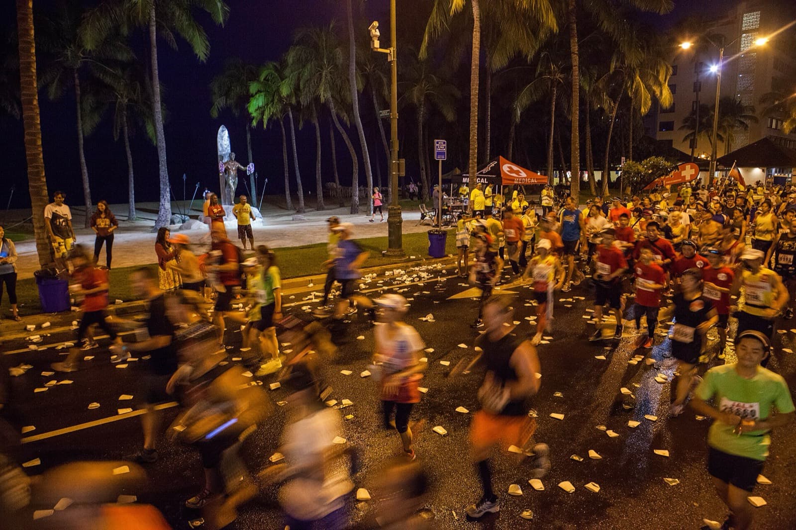 Honolulu Marathon: runners passing the duke kahanamoku statue in waikiki before dawn