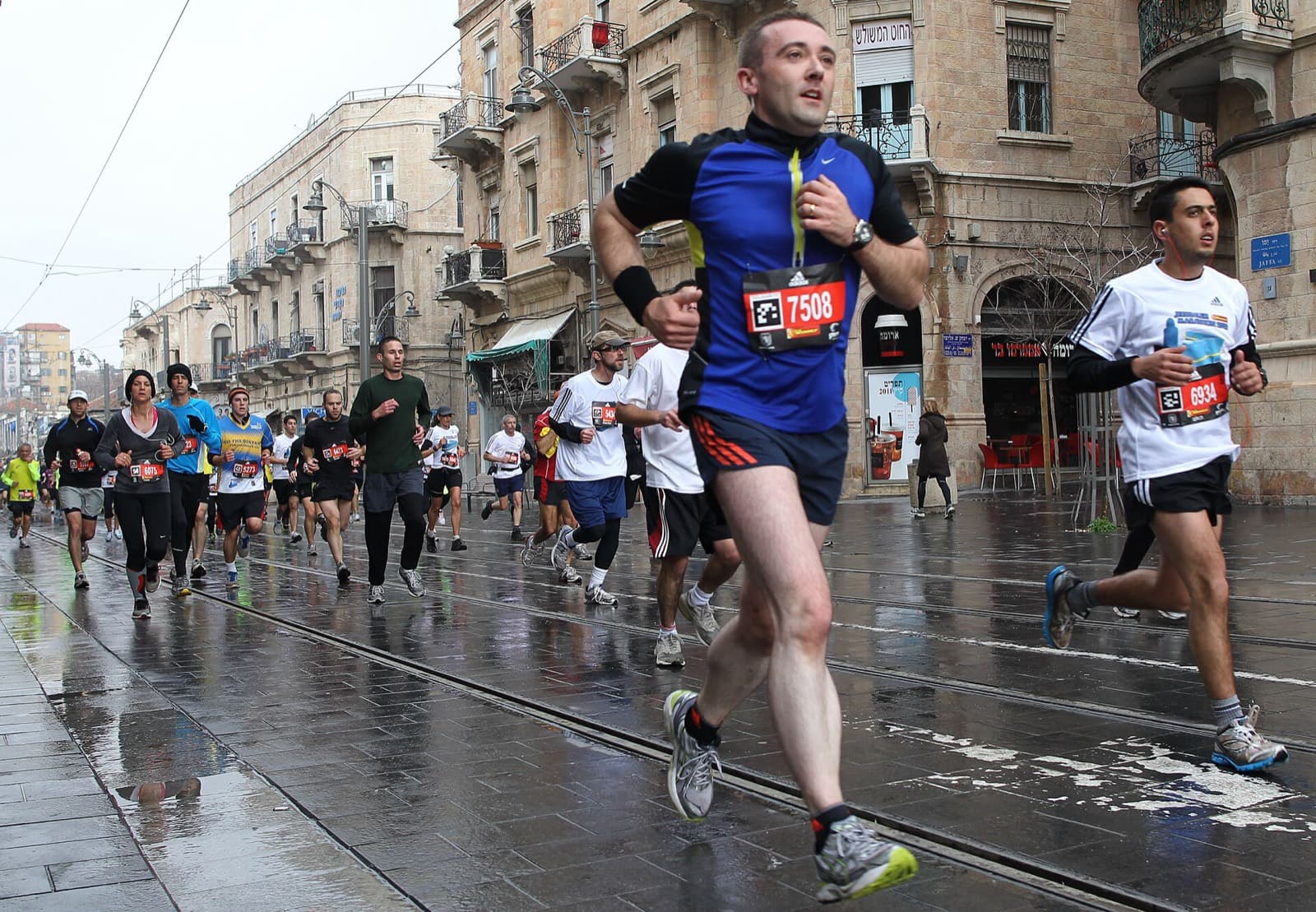Jerusalem Marathon: runners in the rain on a jerusalem street with tram tracks, 2012 race