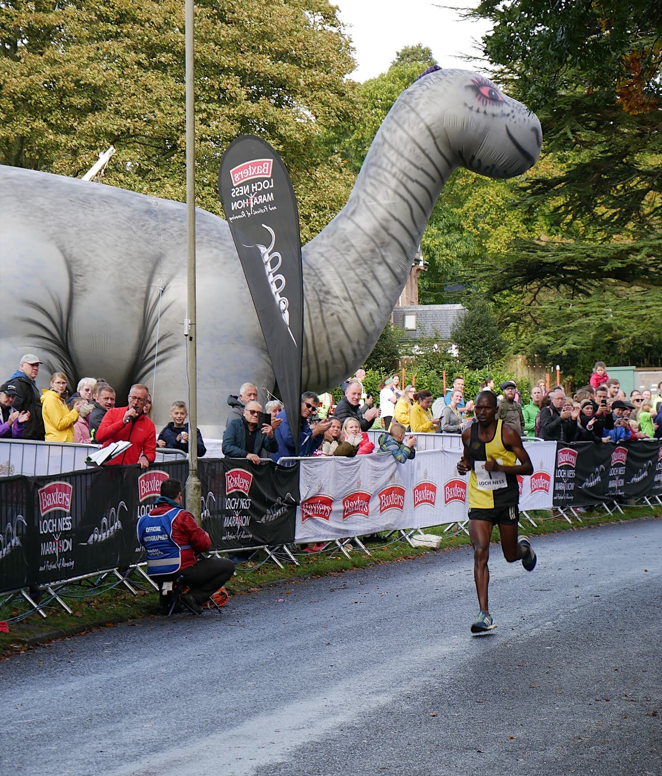 Baxters Loch Ness Marathon: lead runner approaching the bught park finish past crowds and the inflatable nessie, 2019