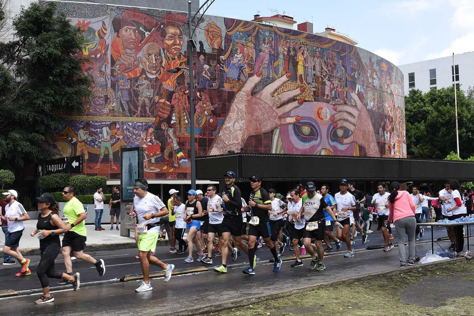 Maratón de la Ciudad de México (Mexico City Marathon): runners on a closed city street passing a large mural