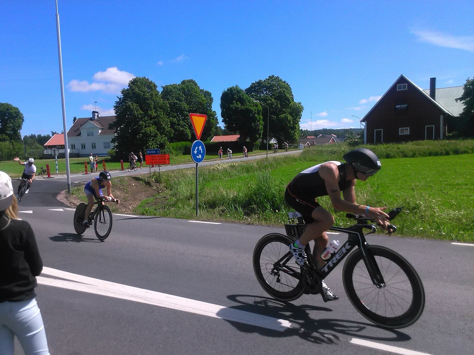 IRONMAN 70.3 Jönköping: cyclists on the ironman jönköping bike course through a village junction