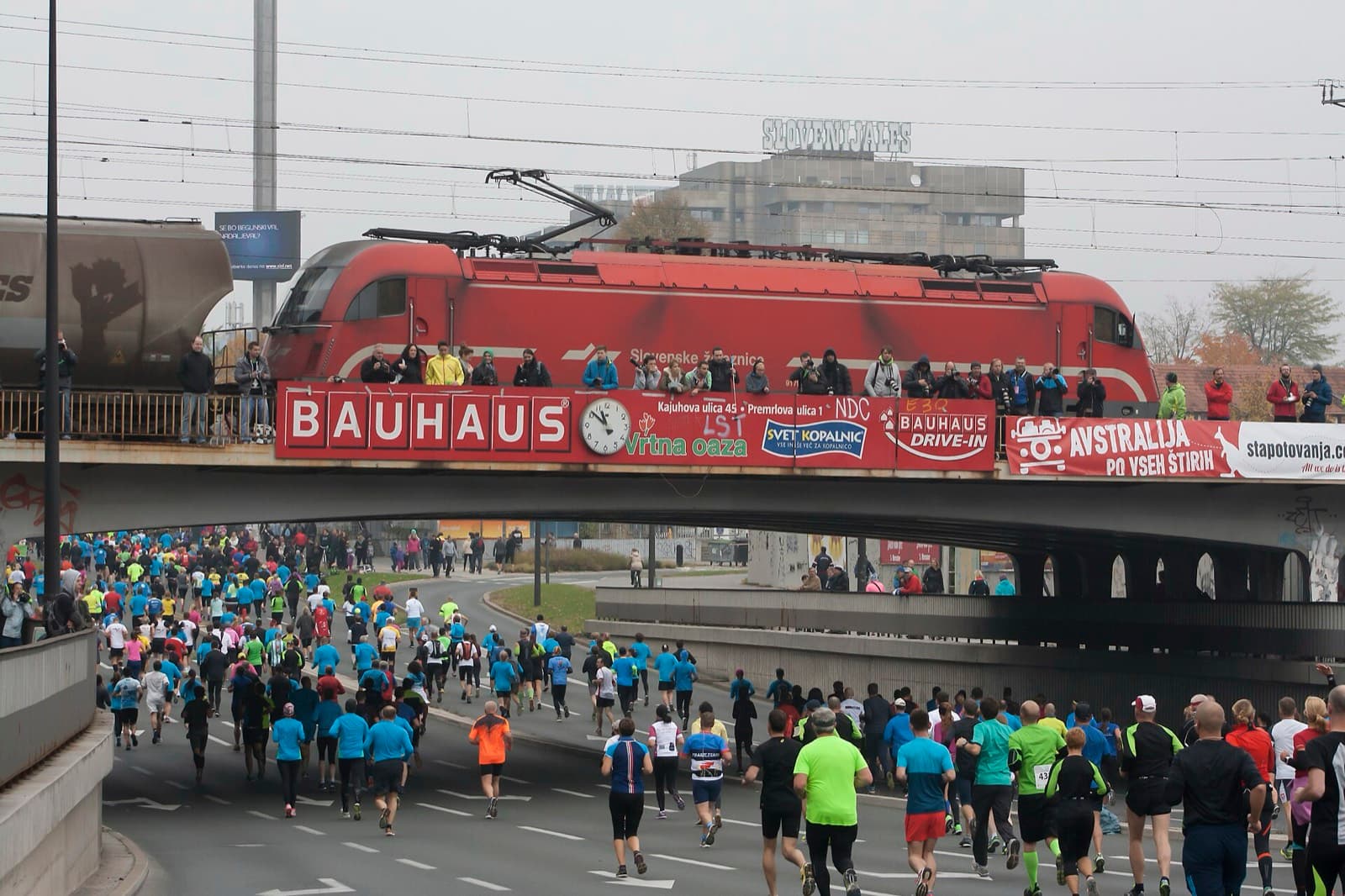 Ljubljana Marathon: runners streaming under a road bridge lined with spectators, ljubljana marathon 2015